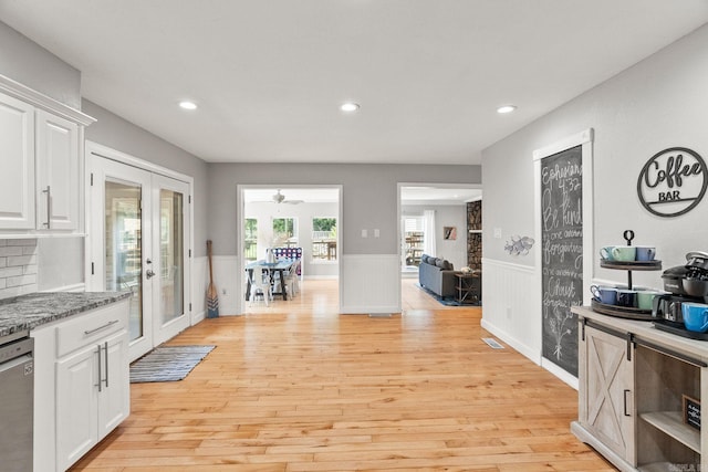 kitchen featuring dark stone countertops, white cabinetry, french doors, light hardwood / wood-style flooring, and stainless steel dishwasher