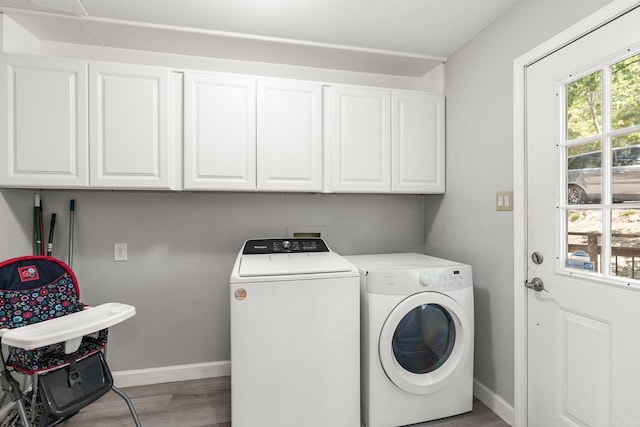 laundry room with washer and clothes dryer, light hardwood / wood-style floors, and cabinets