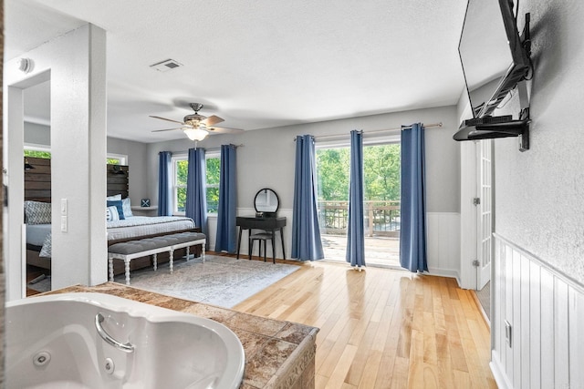 bedroom featuring ceiling fan, light hardwood / wood-style floors, access to outside, and a textured ceiling