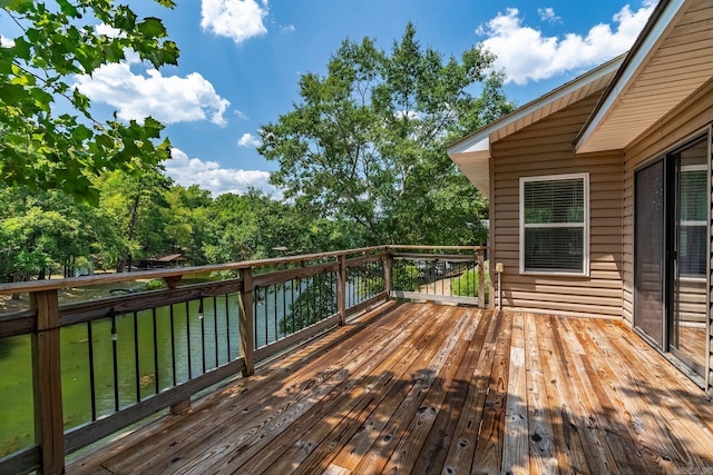 wooden terrace featuring a water view and a lawn