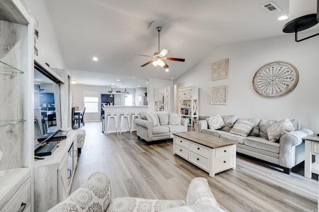 living room featuring ceiling fan, vaulted ceiling, and light wood-type flooring