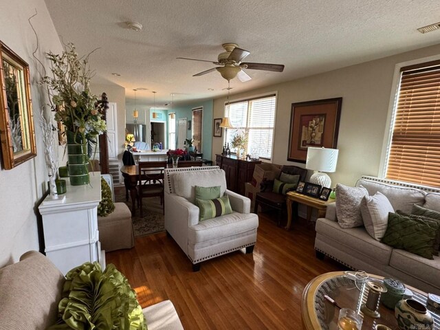 living room with a textured ceiling, ceiling fan, and dark hardwood / wood-style floors