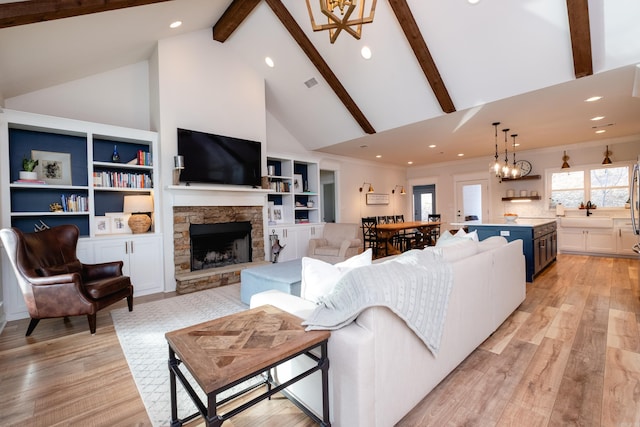 living room featuring a fireplace, light wood-type flooring, high vaulted ceiling, and beamed ceiling