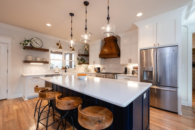 kitchen featuring premium range hood, stainless steel appliances, tasteful backsplash, a kitchen island, and white cabinets