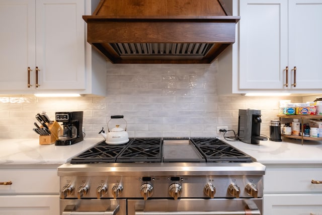 kitchen with white cabinets, high end stove, tasteful backsplash, and custom range hood