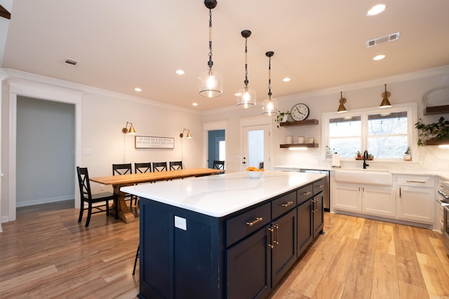 kitchen with a center island, ornamental molding, sink, light hardwood / wood-style flooring, and white cabinetry