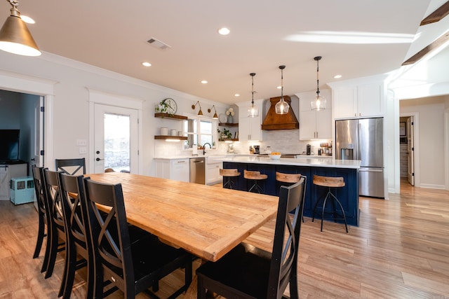 dining area with light wood-type flooring and crown molding