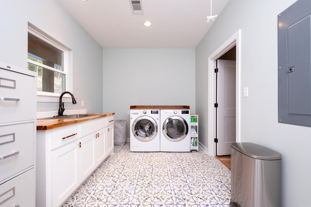 laundry room featuring sink, washing machine and clothes dryer, electric panel, and cabinets