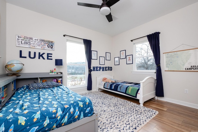 bedroom featuring ceiling fan, wood-type flooring, and multiple windows