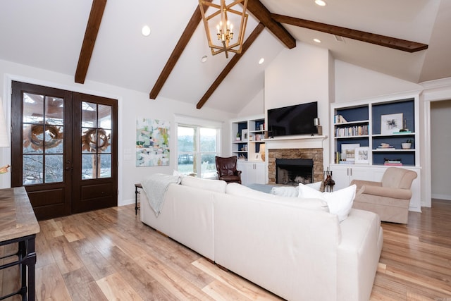 living room with a fireplace, an inviting chandelier, french doors, built in features, and high vaulted ceiling