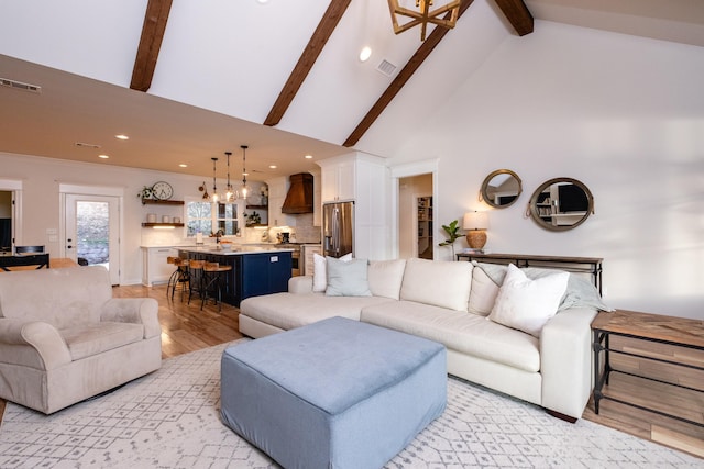 living room with high vaulted ceiling, beam ceiling, and light wood-type flooring