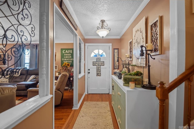 foyer entrance with ornamental molding, a textured ceiling, and light hardwood / wood-style floors