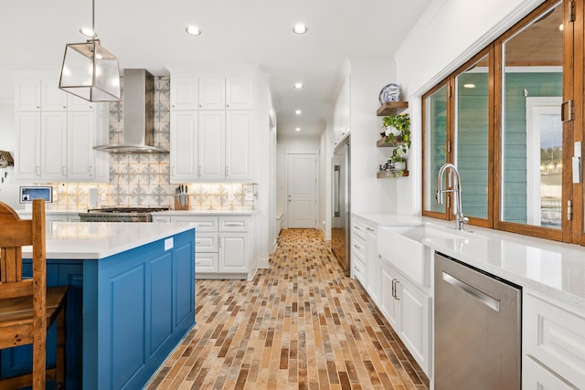 kitchen with pendant lighting, wall chimney range hood, decorative backsplash, white cabinetry, and appliances with stainless steel finishes