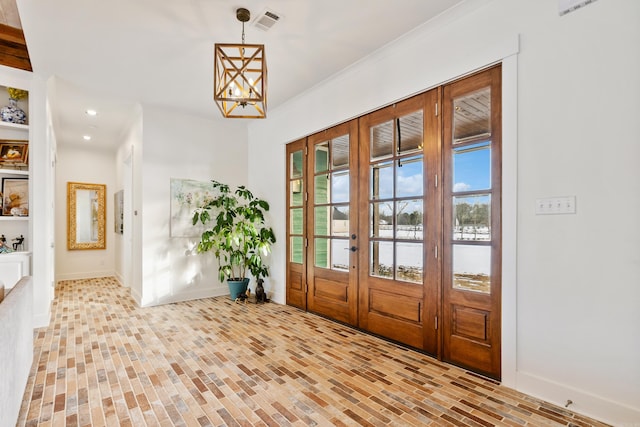 entryway featuring a notable chandelier, french doors, and ornamental molding