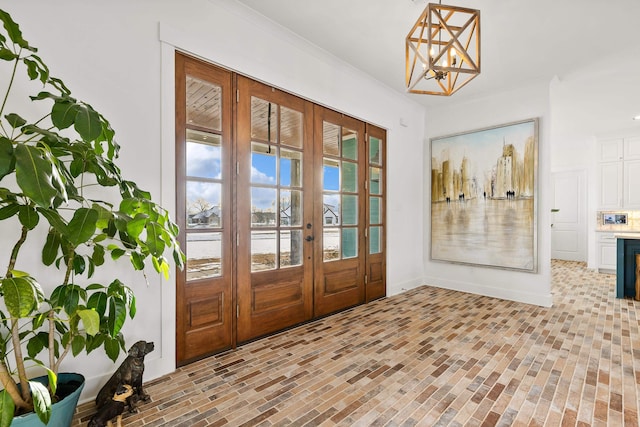 doorway featuring ornamental molding, french doors, and an inviting chandelier