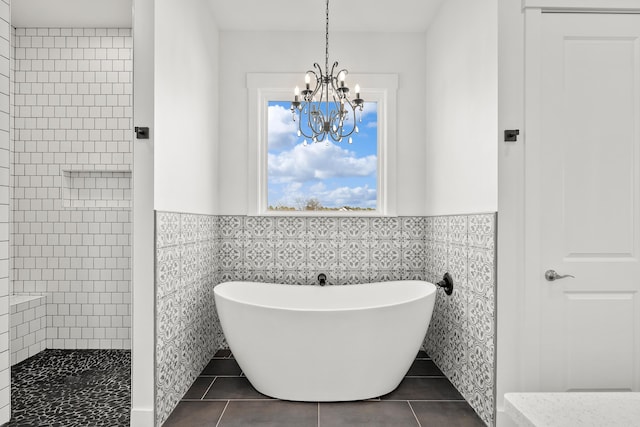 bathroom with shower with separate bathtub, tile patterned flooring, tile walls, and an inviting chandelier