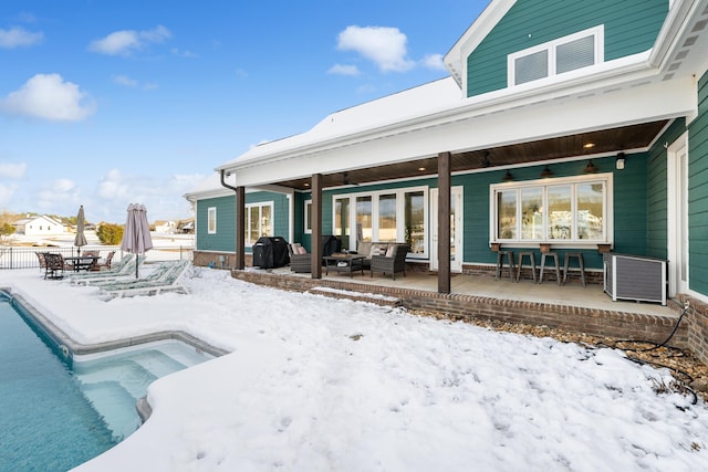 snow covered rear of property with a patio area, ceiling fan, and outdoor lounge area