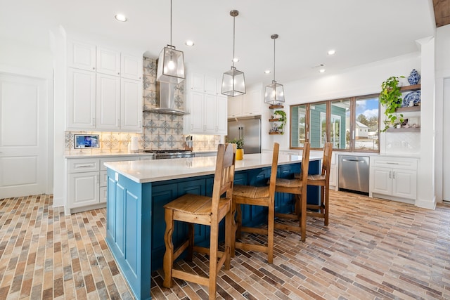 kitchen featuring stainless steel appliances, white cabinets, wall chimney exhaust hood, decorative backsplash, and a kitchen island