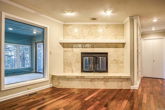 room details with a tile fireplace, crown molding, and wood-type flooring