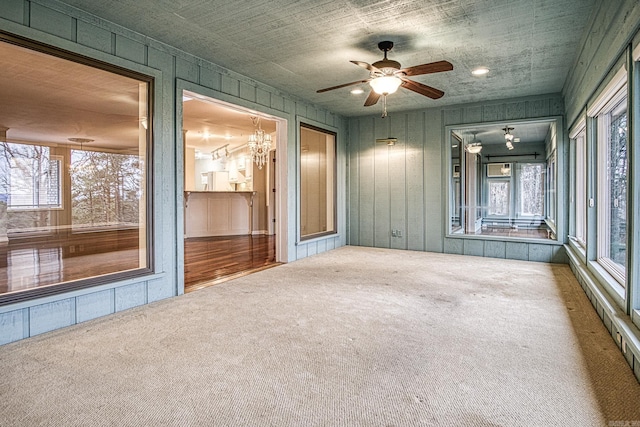 interior space with ceiling fan with notable chandelier and carpet flooring