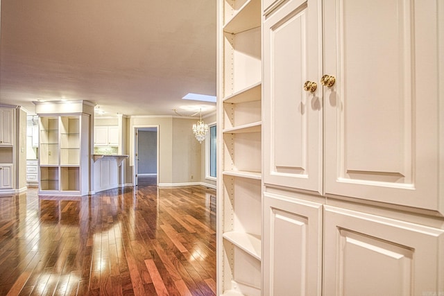 unfurnished living room featuring a skylight, dark hardwood / wood-style flooring, and a chandelier