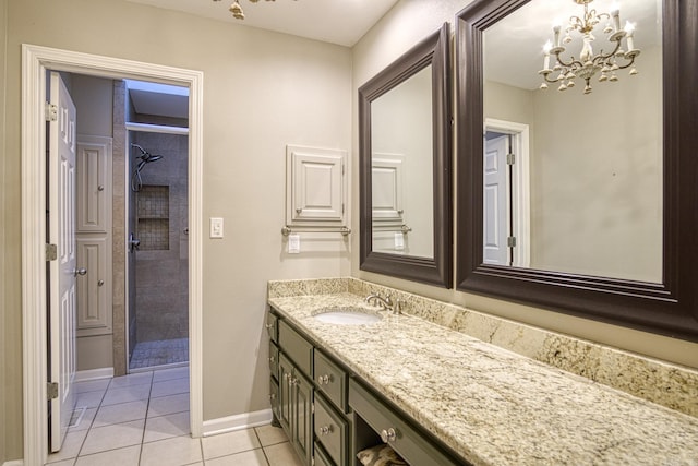 bathroom with tile patterned flooring, a tile shower, a chandelier, and vanity