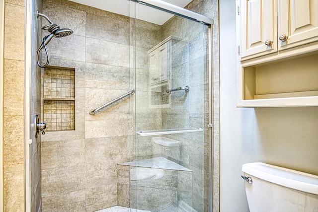 bathroom featuring toilet and a shower with shower door