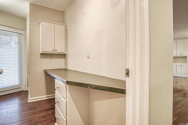 kitchen featuring white cabinets, dark hardwood / wood-style flooring, and built in desk