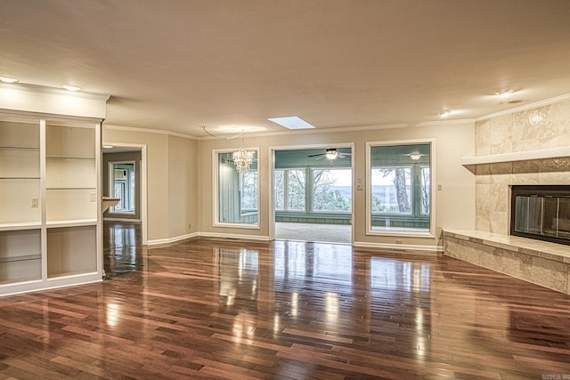 unfurnished living room with a fireplace, ornamental molding, a notable chandelier, and dark wood-type flooring