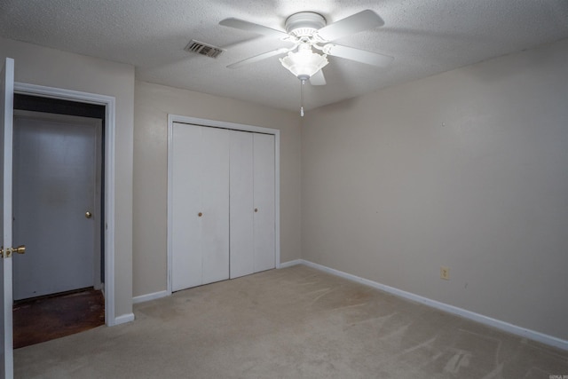 unfurnished bedroom with ceiling fan, a textured ceiling, a closet, and light carpet