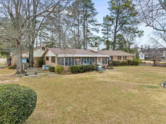 view of front of property featuring central AC unit, a front yard, and a sunroom