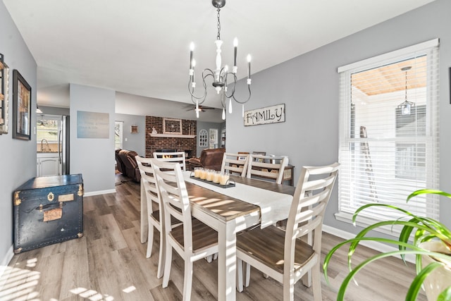 dining space featuring a fireplace, hardwood / wood-style flooring, a chandelier, and sink