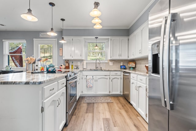 kitchen with appliances with stainless steel finishes, hanging light fixtures, white cabinets, backsplash, and sink