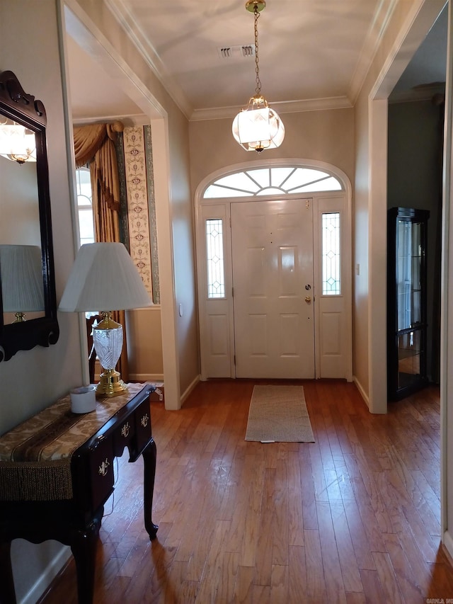 entrance foyer with wood-type flooring, ornamental molding, and plenty of natural light