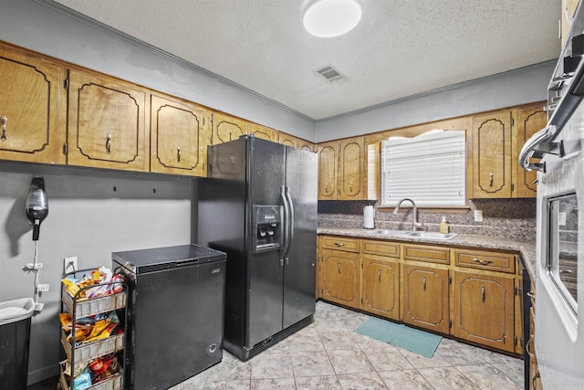 kitchen featuring a textured ceiling, light tile patterned floors, black refrigerator with ice dispenser, backsplash, and sink