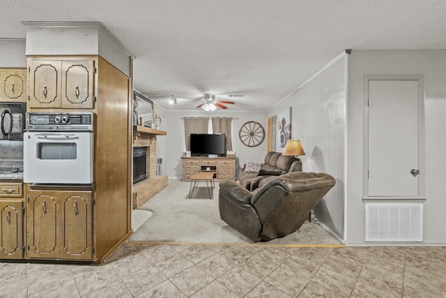 living room featuring a fireplace, a textured ceiling, ceiling fan, and crown molding