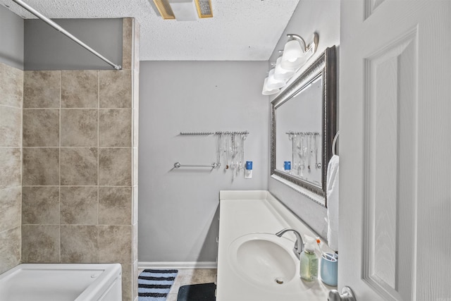 bathroom featuring a textured ceiling, walk in shower, and vanity