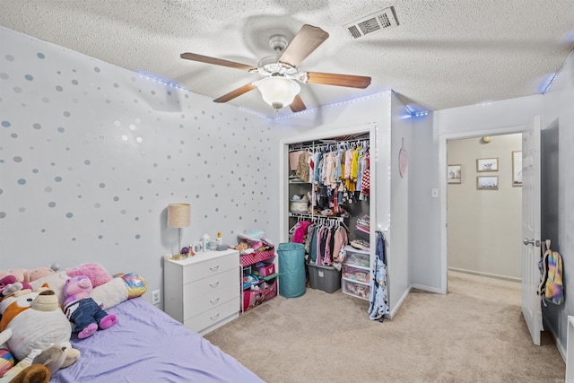 bedroom with a textured ceiling, light colored carpet, ceiling fan, and a closet