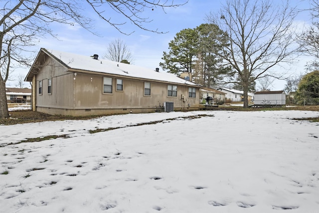 snow covered back of property featuring central AC