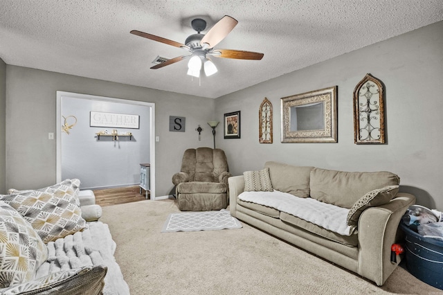 living room with a textured ceiling, carpet floors, and ceiling fan