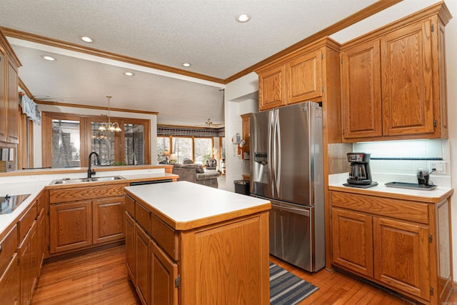 kitchen with hanging light fixtures, a notable chandelier, stainless steel refrigerator with ice dispenser, a kitchen island, and sink