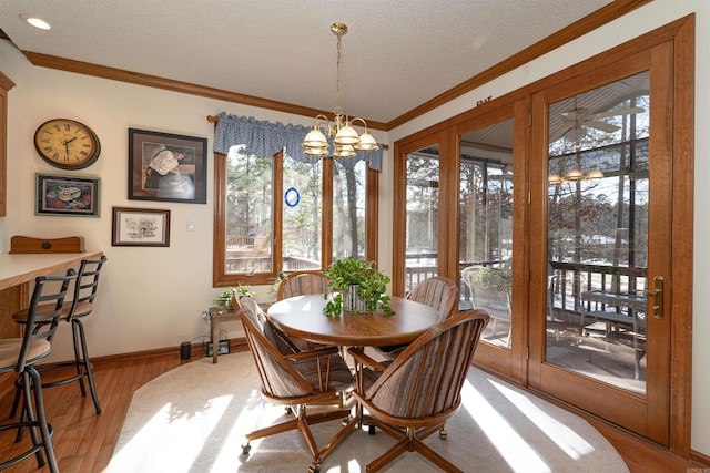 dining space with an inviting chandelier, light hardwood / wood-style floors, a textured ceiling, and a healthy amount of sunlight