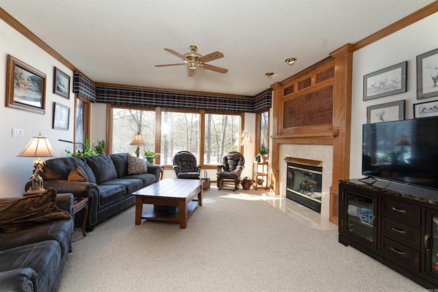 carpeted living room with ornamental molding, a textured ceiling, a tiled fireplace, and ceiling fan