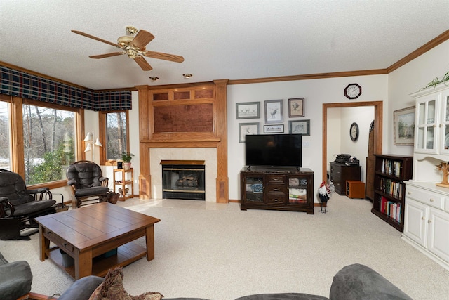 living room with a tile fireplace, light carpet, crown molding, ceiling fan, and a textured ceiling