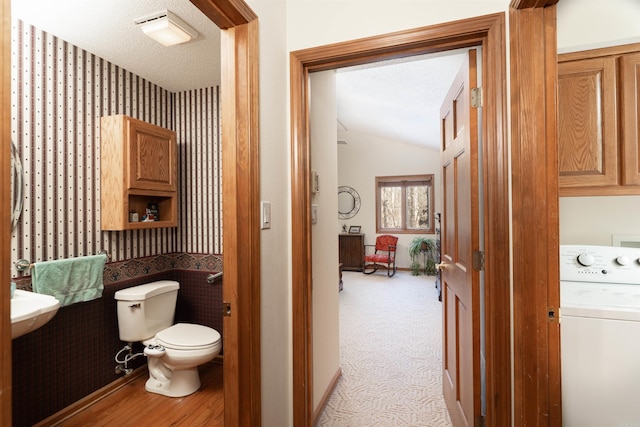 bathroom featuring toilet, washer / clothes dryer, and a textured ceiling