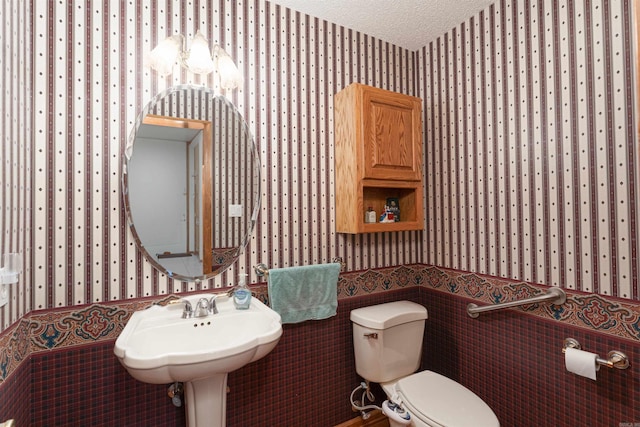 bathroom with a textured ceiling, sink, and toilet