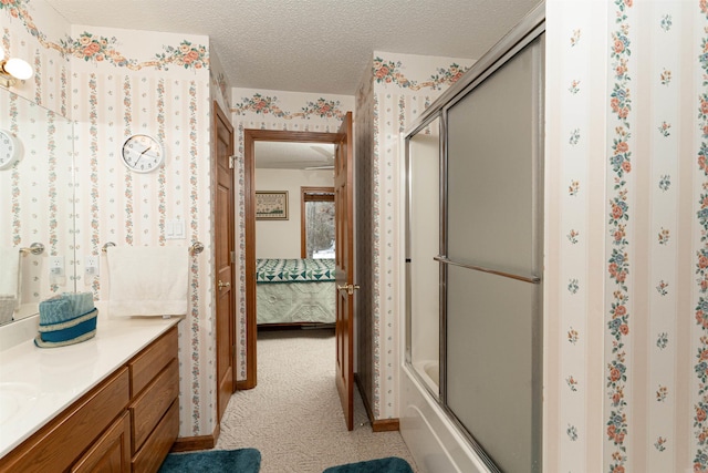 bathroom featuring combined bath / shower with glass door, vanity, and a textured ceiling