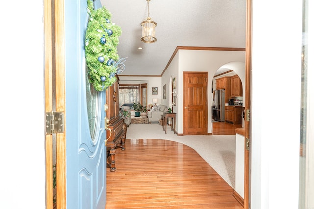 entrance foyer featuring carpet floors, a textured ceiling, and crown molding