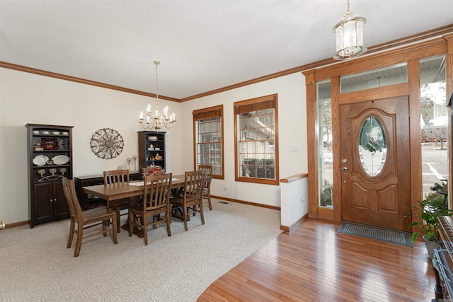 dining room with ornamental molding, hardwood / wood-style flooring, and a notable chandelier