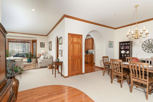 dining area featuring an inviting chandelier, light carpet, a textured ceiling, and ornamental molding